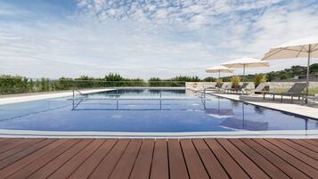 Una piscina al aire libre de temporada, sombrillas