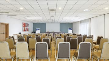 Ein Konferenzraum mit Reihen von Stühlen, einem Rednerpult und einem Tisch mit einem Laptop.