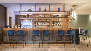 A bar area with a wooden counter, multiple shelves of bottles, and six blue bar stools. - voco Venice Mestre - The Quid by IHG (Mestre)