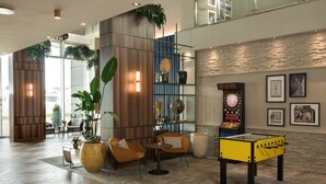 A lobby with a foosball table, seating area, and a dartboard. - voco Venice Mestre - The Quid by IHG (Mestre)