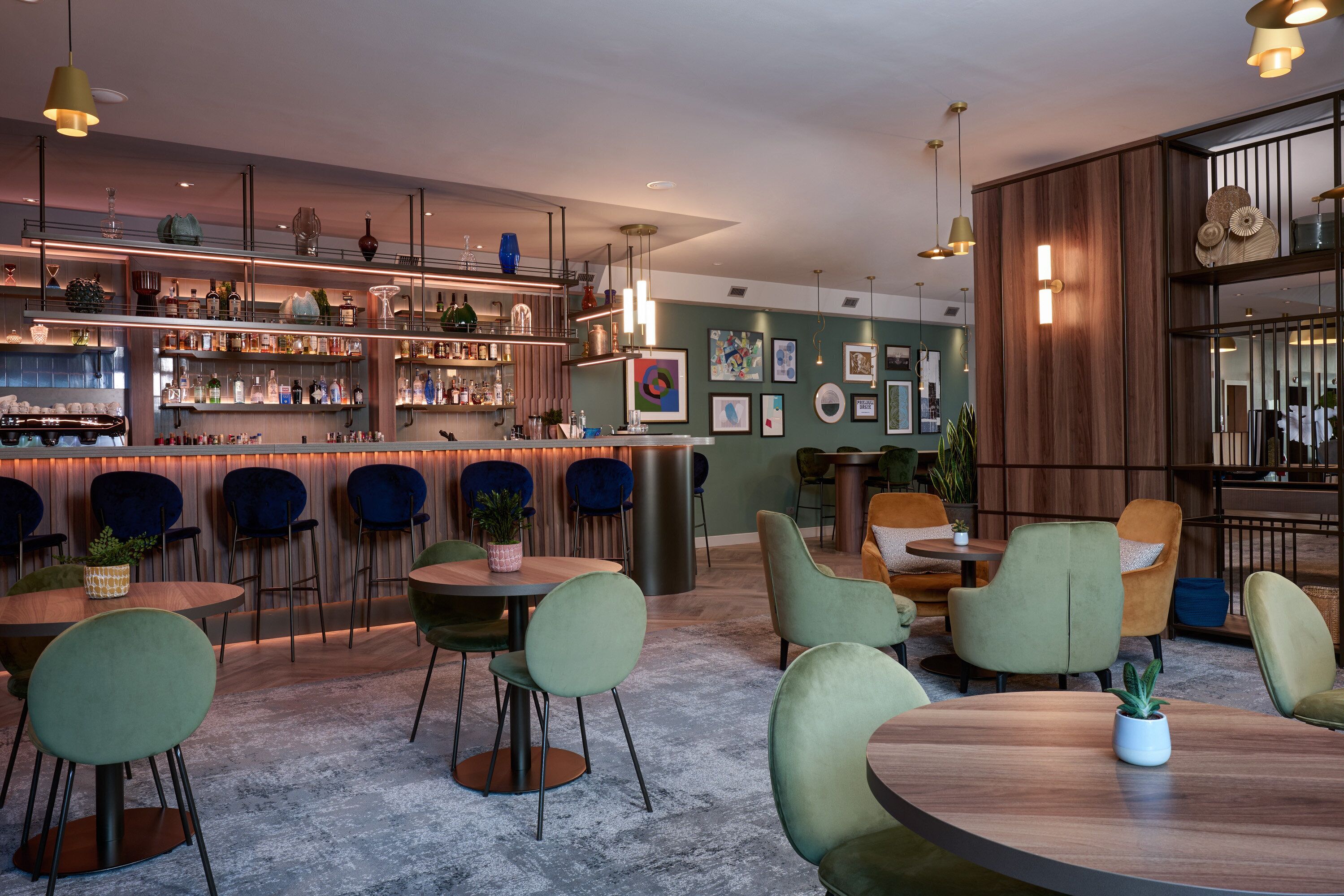 A modern bar area with multiple seating options, including round tables and chairs, and a variety of bar shelves stocked with bottles.