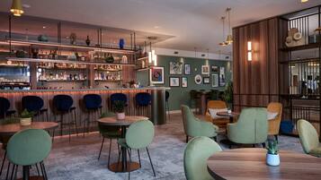 Zona de bar moderna con diversas opciones de asientos, incluyendo mesas redondas y sillas, y varios estantes repletos de botellas.