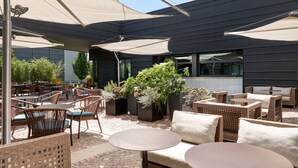 An outdoor patio area with wicker furniture, large umbrellas, and potted plants. - voco Venice Mestre - The Quid by IHG (Mestre)