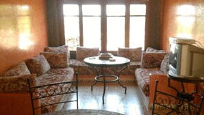 A cozy living room with a sofa set, a small round table, and a television. - Riad Dar Fatna (Ait Taguella)