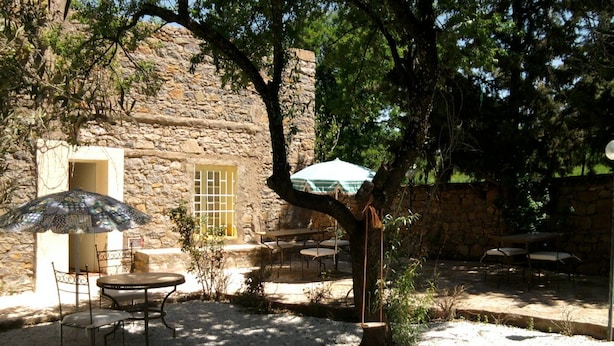 A stone building with outdoor seating and a tree providing shade. - Riad Dar Fatna (Ait Taguella)