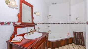 Un baño con tocador de madera, un espejo grande, un lavamanos blanco, una bañera y una zona de ducha.