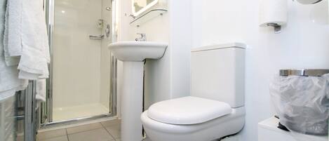 A modern bathroom with a glass shower enclosure, a pedestal sink, and a toilet.