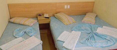 Two twin beds with matching headboards, each with a bedside table, a lamp, and a telephone.