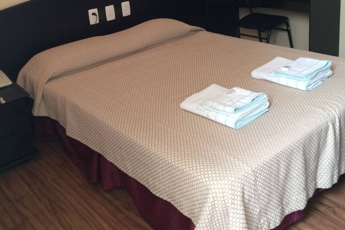 A hotel room with a bed, a desk, and a chair.
