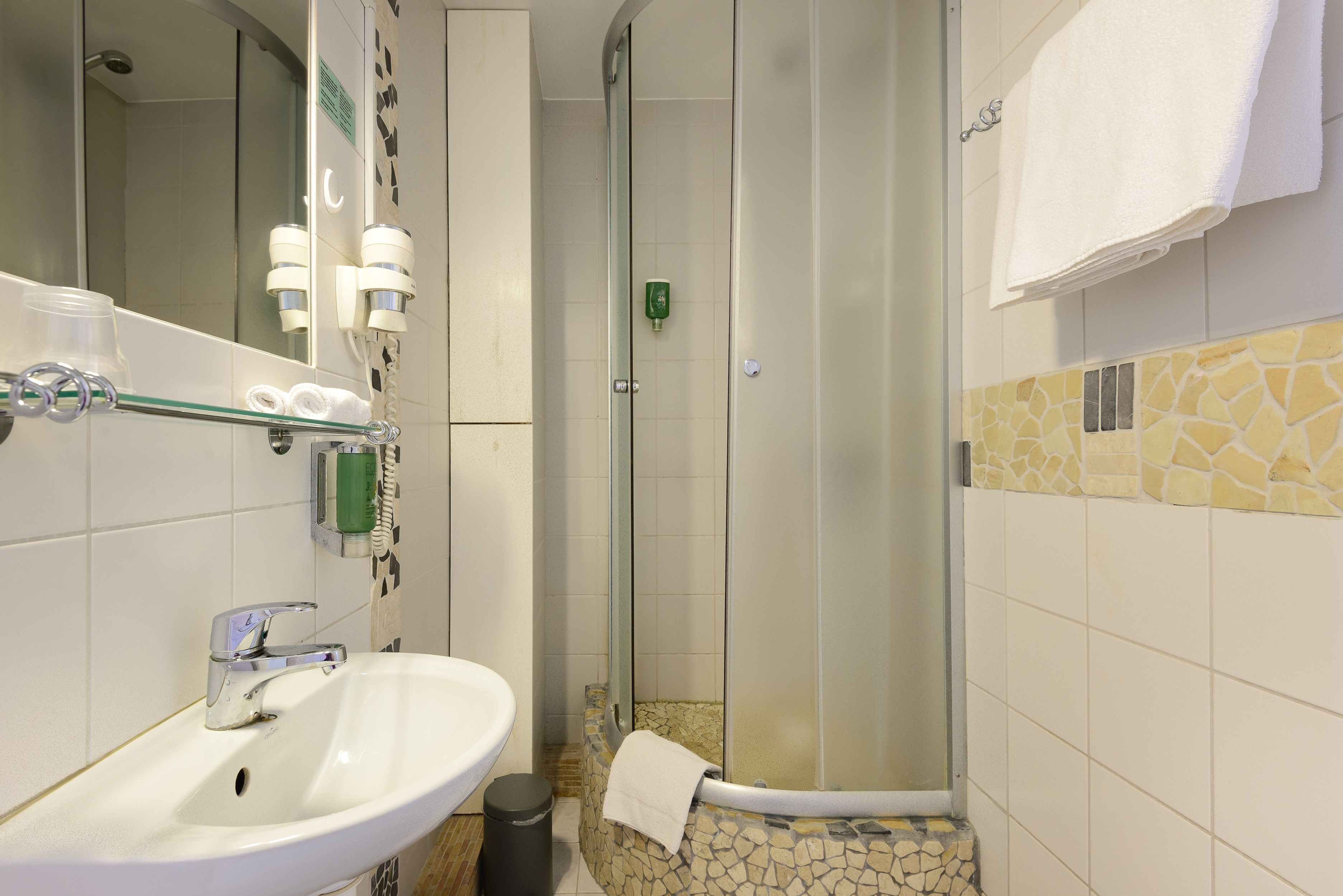 A bathroom with a white sink, a glass shower enclosure, and a mirror.