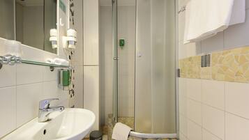 A bathroom with a white sink, a glass shower enclosure, and a mirror.