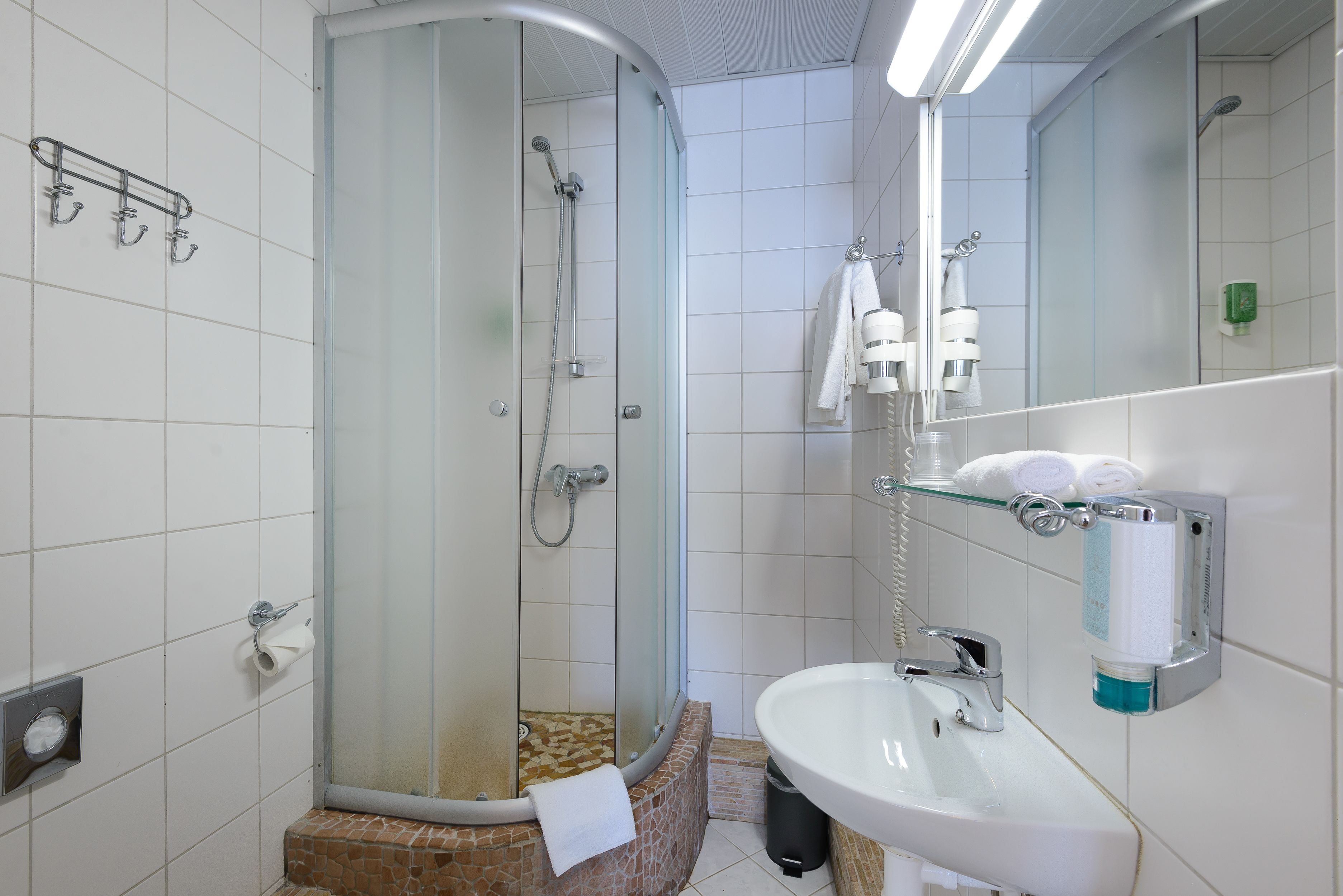 Une salle de bain moderne avec une douche à parois de verre, un lavabo et un miroir.