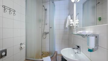 Une salle de bain moderne avec une douche à parois de verre, un lavabo et un miroir.