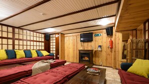 A wooden interior with a fireplace, seating area, and a television. - Hotel Hansalinn (Parnu)