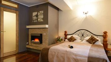 A bedroom with a fireplace, a bed with a headboard, and a door.