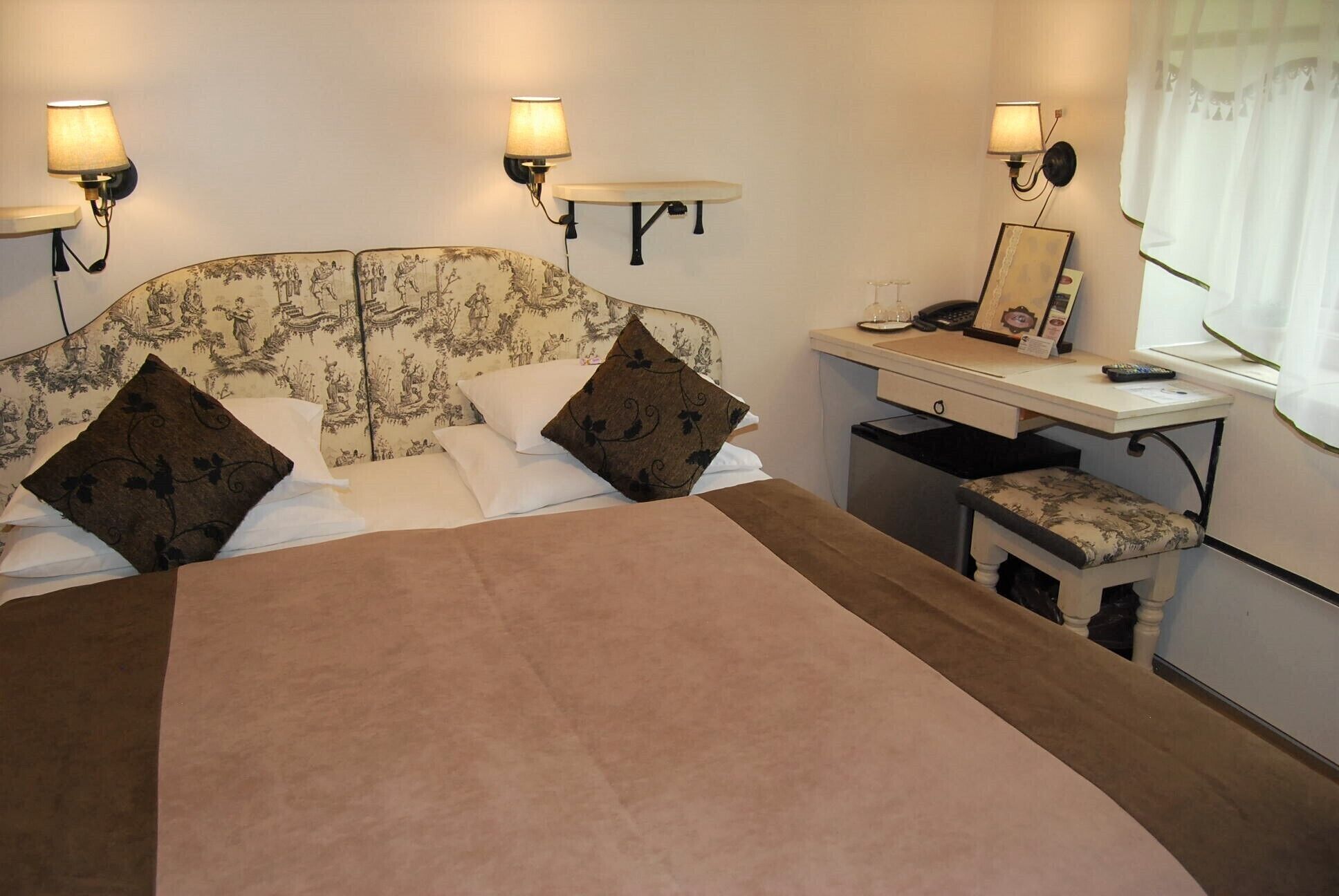 Una habitación de hotel con cama, mesita de noche, lámpara y escritorio con silla.