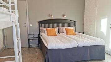 A bedroom with a bed, a nightstand, a ladder, and a brick wall.