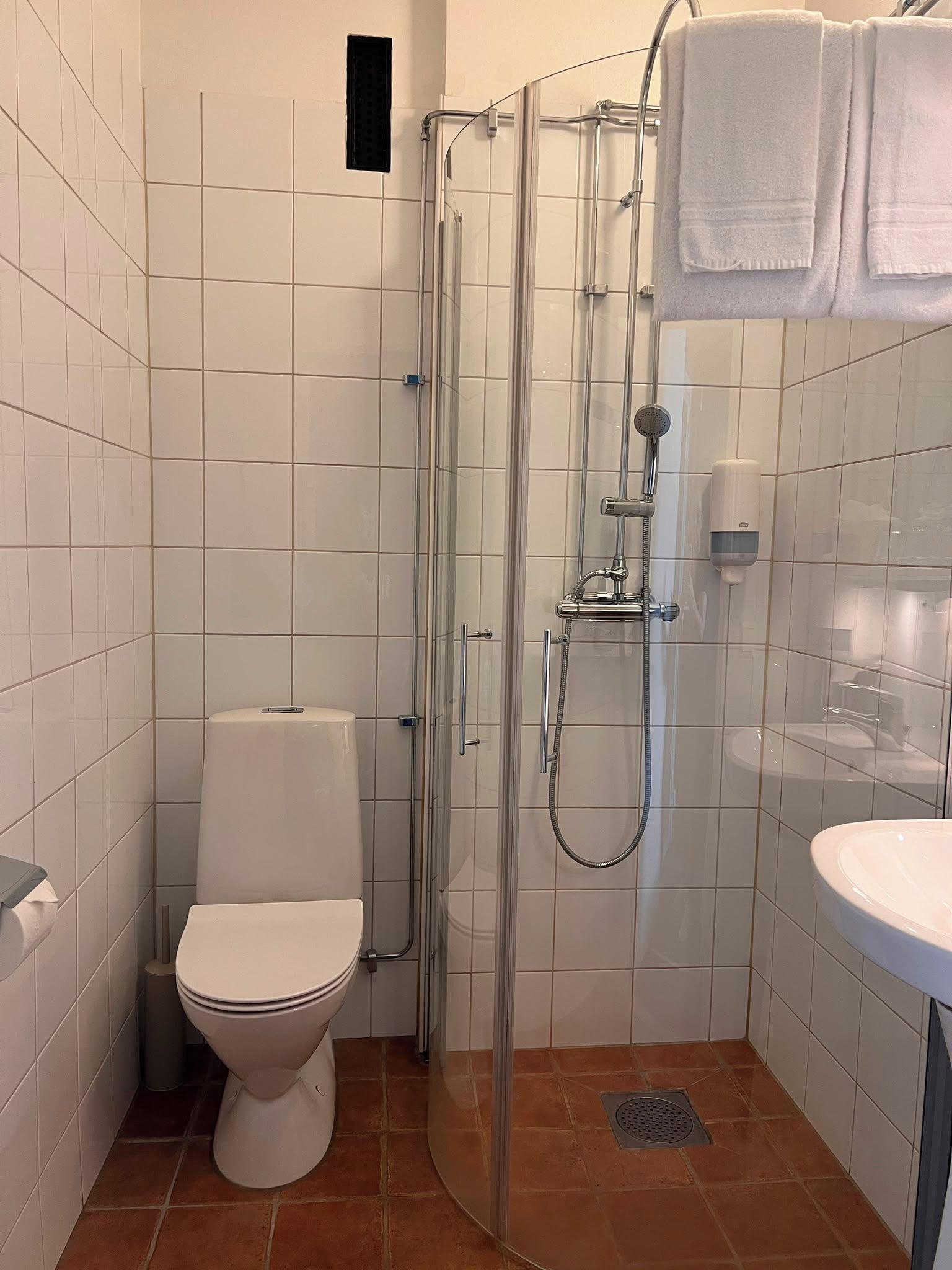 A bathroom with a glass-enclosed shower, a toilet, and a sink.