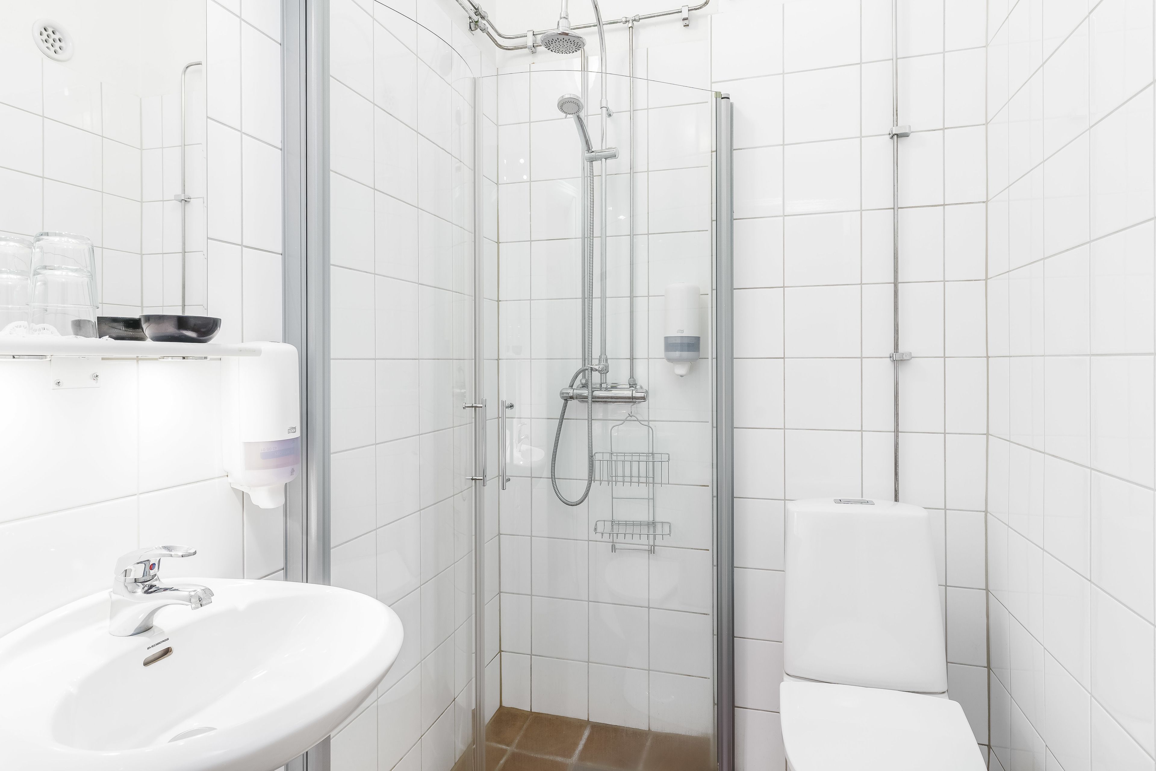 Une salle de bain moderne avec une douche à parois de verre, un lavabo blanc et des toilettes.