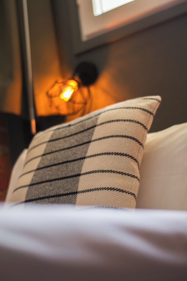 Primer plano de un almohadón con estampado de cuadros sobre una cama.