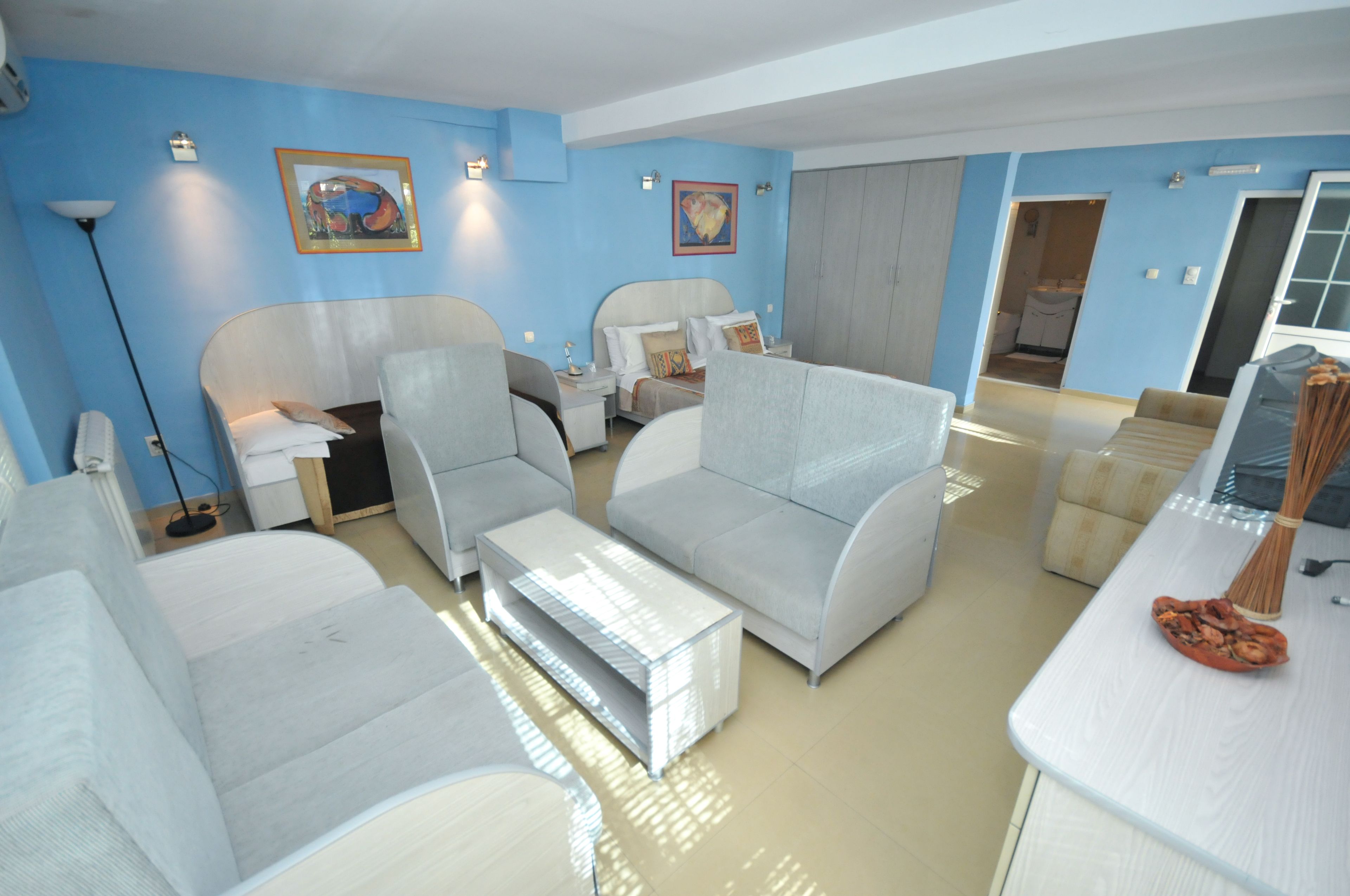 A modern living room with a sofa, armchairs, a coffee table, and a dining area with a table and chairs.