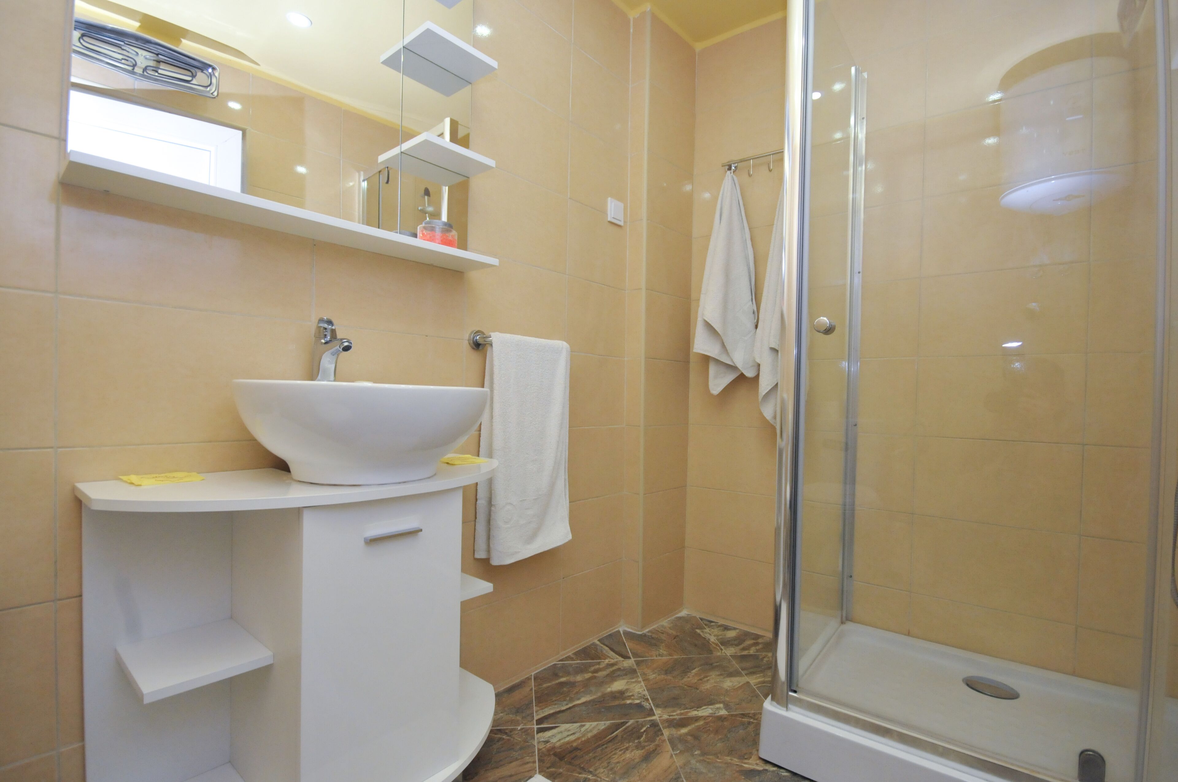 Een badkamer met een witte wastafel, spiegel en douche.