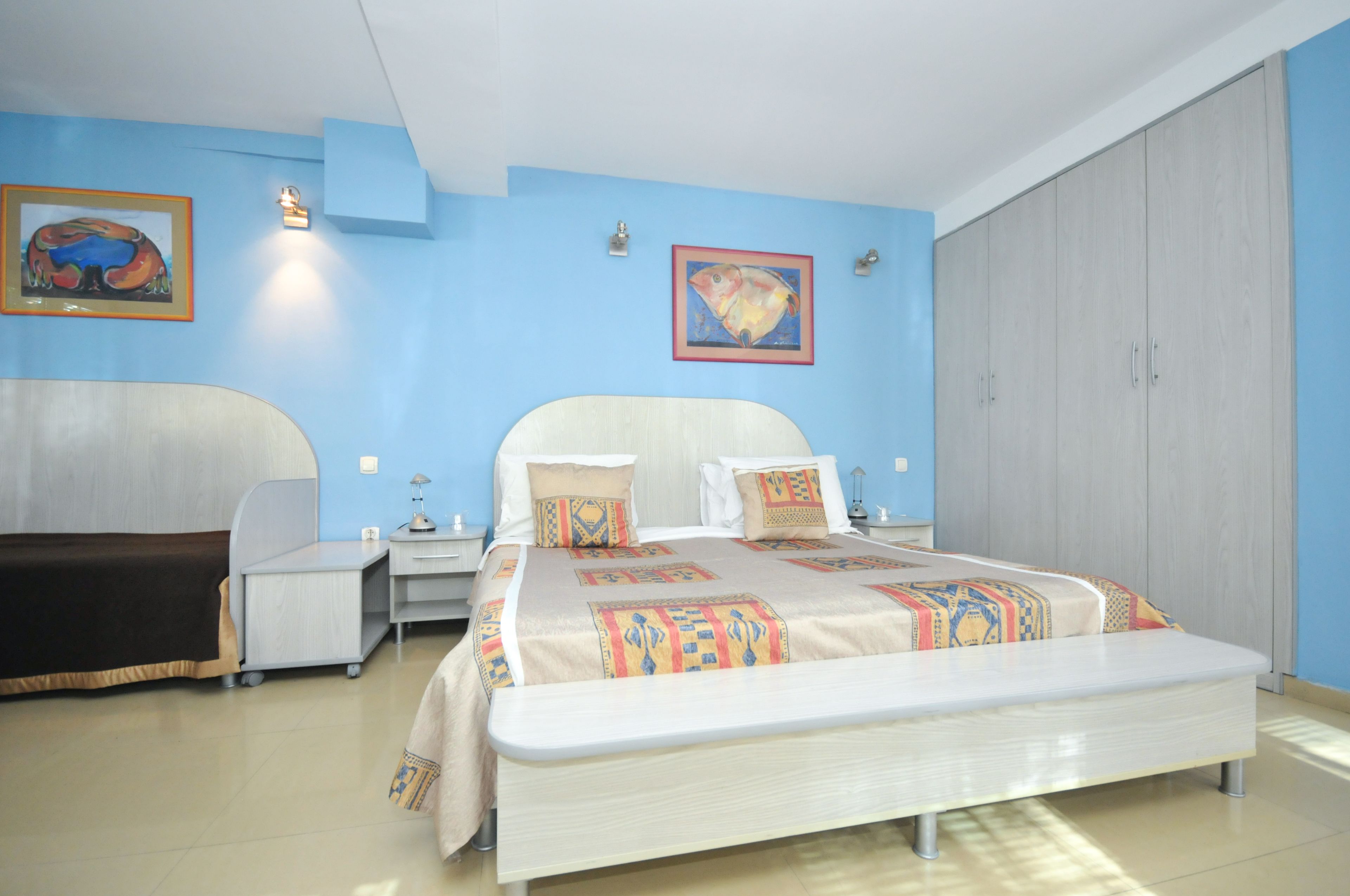 A bedroom with a large bed, bedside tables, a wardrobe, and two wall-mounted lamps.