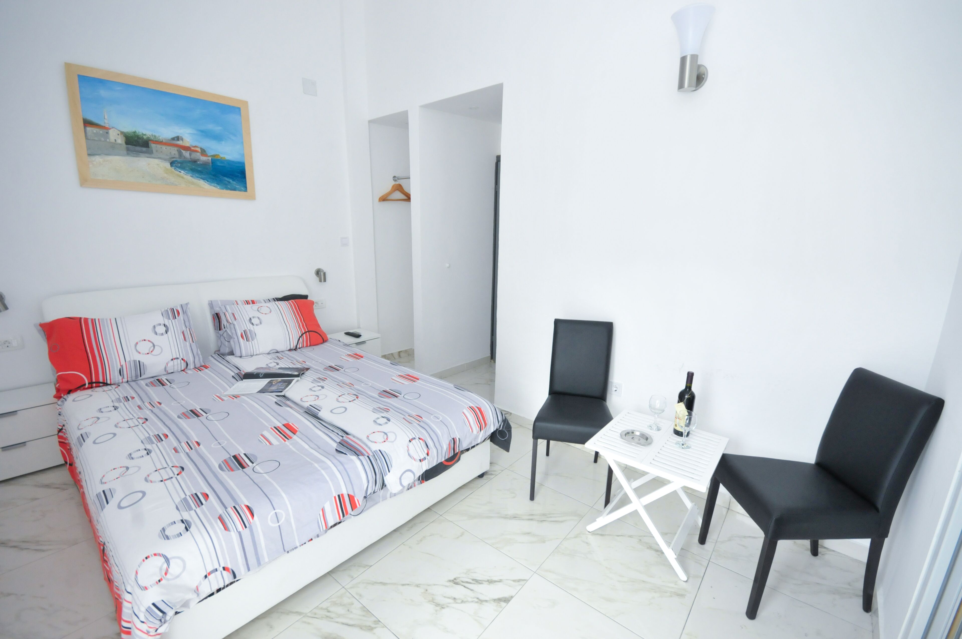 Une chambre d’hôtel avec un lit, deux chaises, une petite table et un tableau au mur.