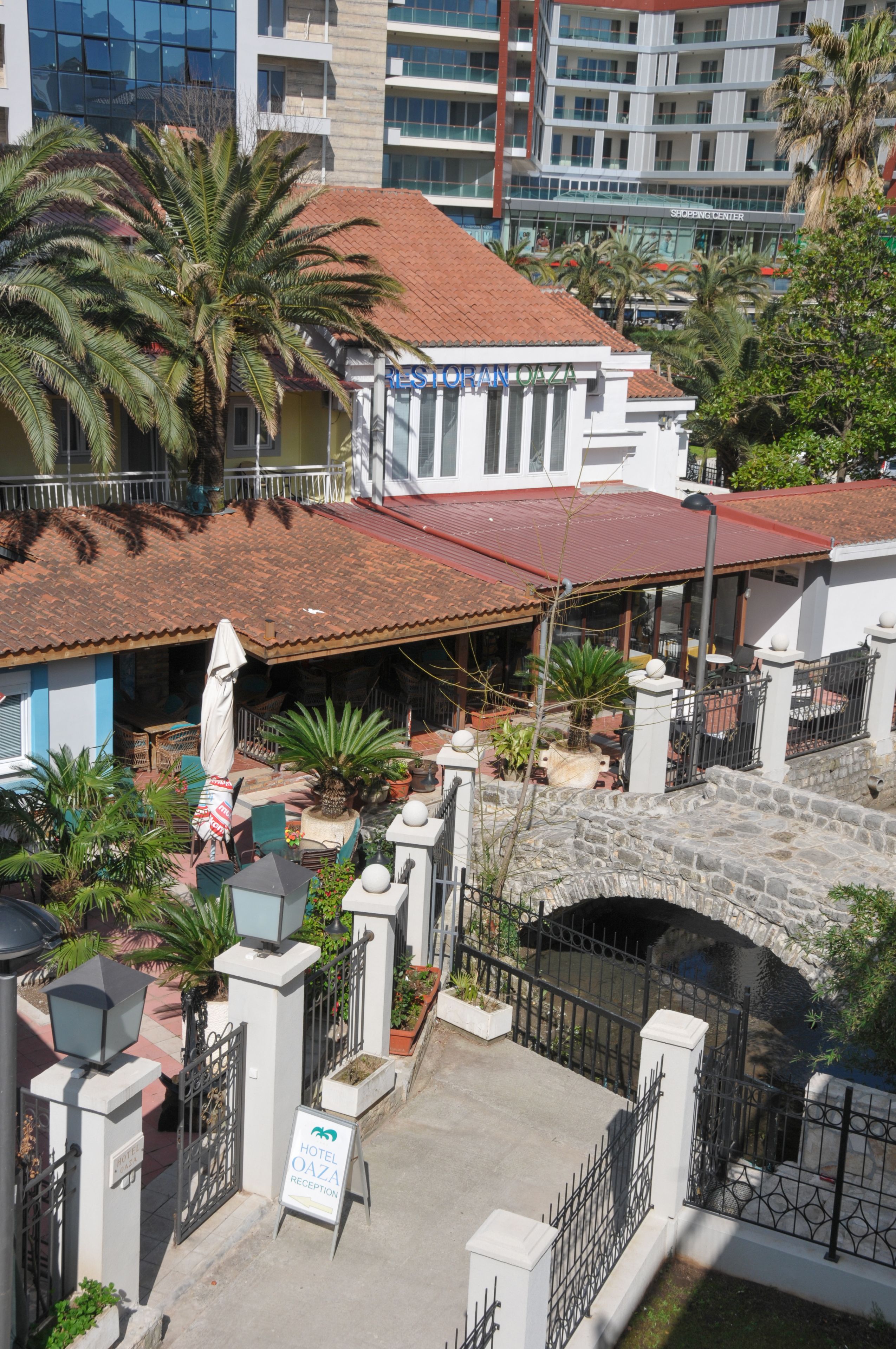 Ένα ξενοδοχείο με κόκκινη κεραμοσκεπή, ένα πέτρινο αψιδωτό τόξο και μια πινακίδα που υποδεικνύει την είσοδο της ρεσεψιόν.
