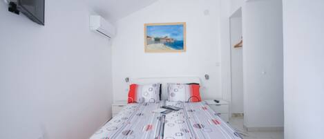 Un dormitorio con una cama, un cuadro en la pared y un televisor montado.