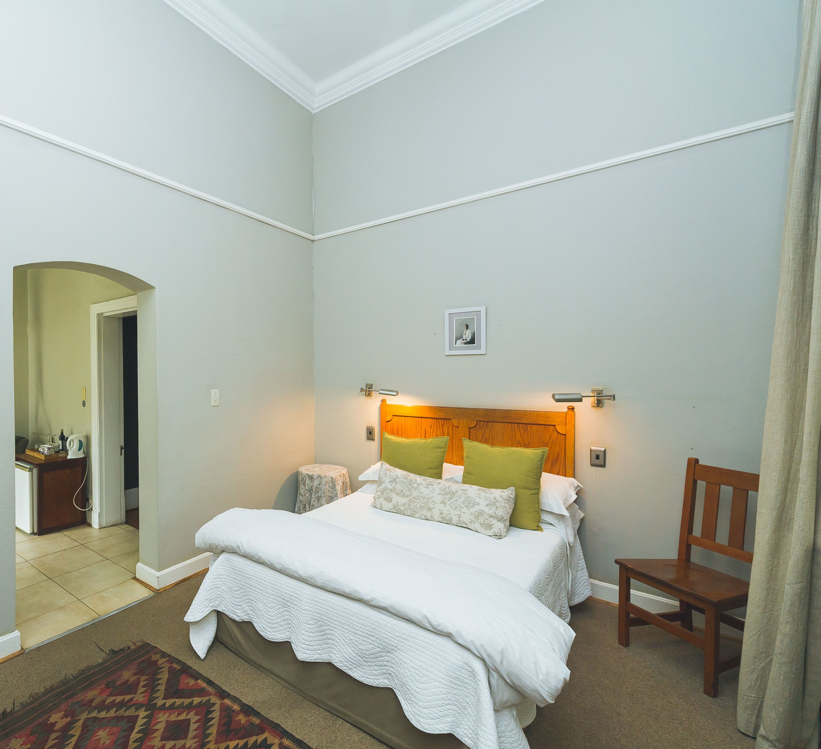 A neatly arranged bedroom with a bed, bedside table, and a chair.