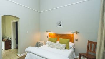 A neatly arranged bedroom with a bed, bedside table, and a chair.
