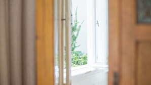 Vista a través de un umbral abierto a un cuarto con ventana que da a una planta verde.