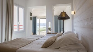 A bedroom with a bed, a view of the outdoors, and a hanging light fixture. - Grand Hôtel du Lido (Argelès-sur-Mer)