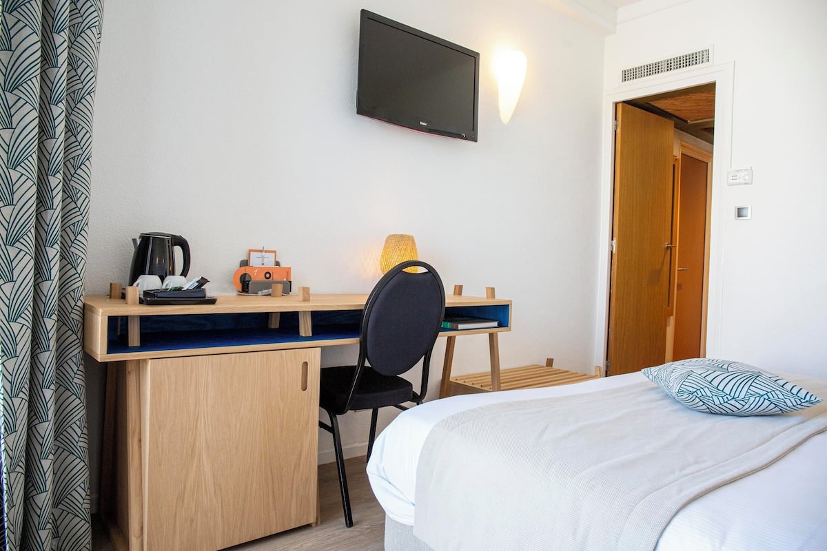 Un dormitorio con una cama, un escritorio con una silla, un televisor y una puerta.