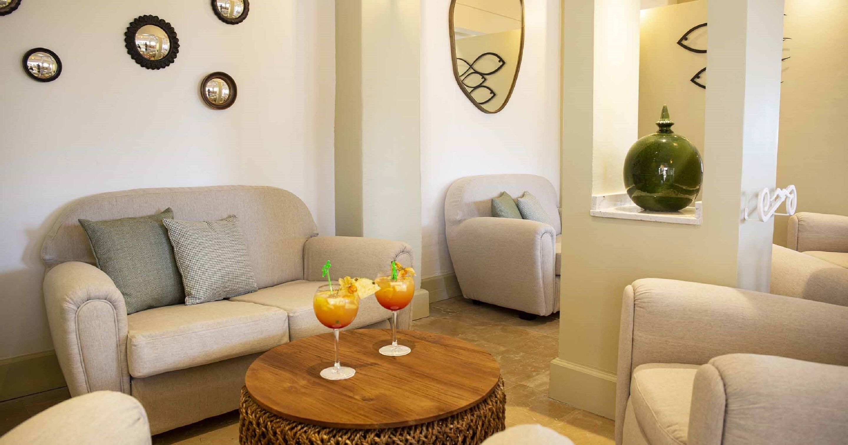 Un salón moderno con un sofá color beige, una mesa de centro redonda de madera y dos bebidas.