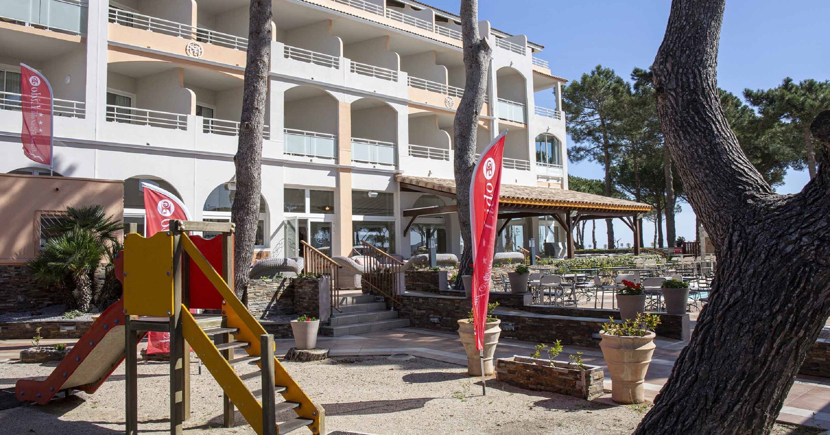 A hotel with a multi-level structure, outdoor seating area, and a children's play area.