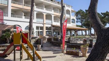 Een hotel met een meerlaagse structuur, een terras en een speelplaats voor kinderen.