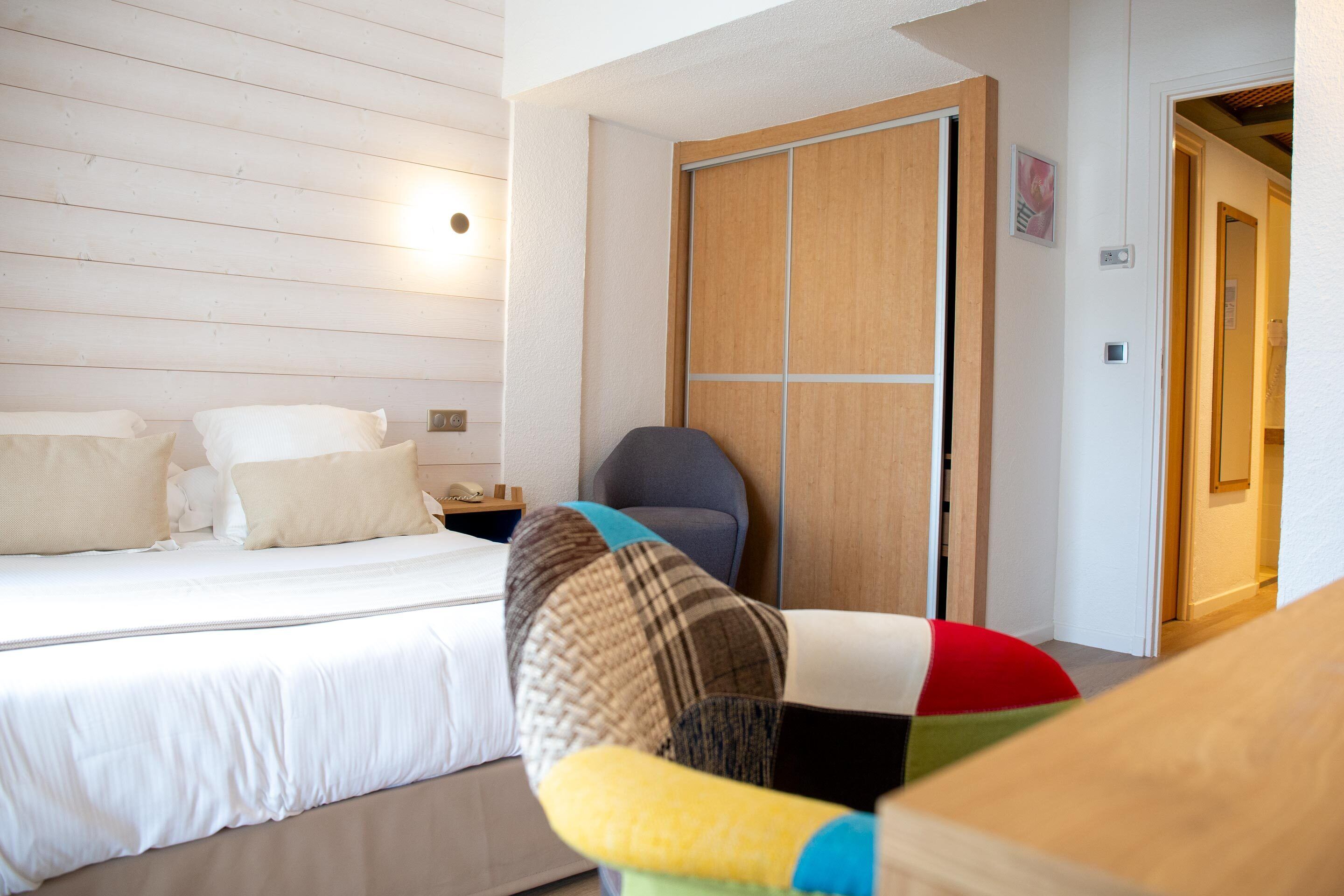 Een hotelkamer met een bed, een stoel, een kledingkast en een nachtkastje.
