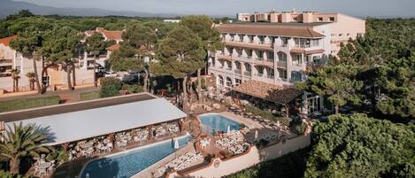 A hotel with a pool, outdoor seating, and a view of the surrounding landscape.