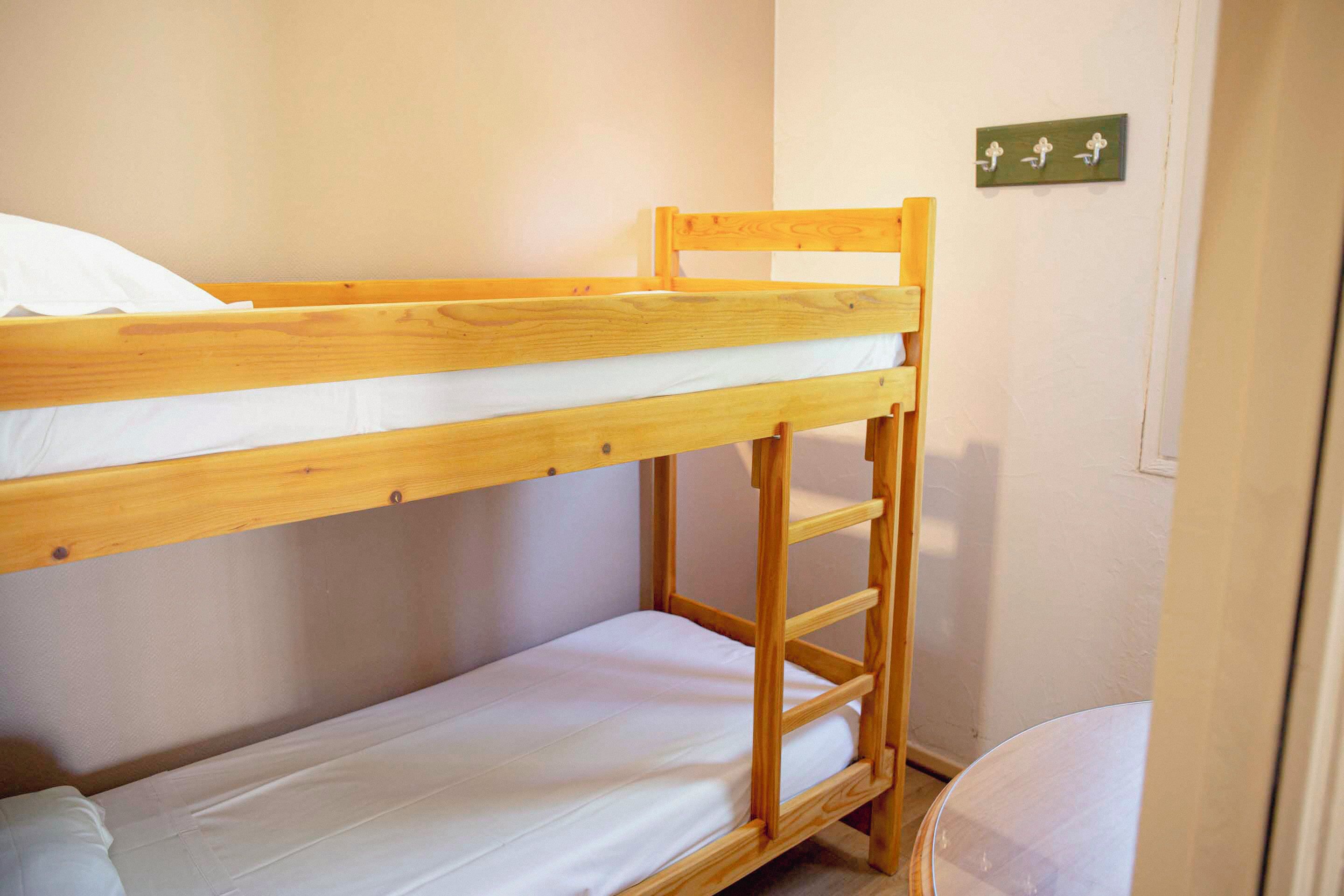 Ein Stockbett mit Holzrahmen und weißer Bettwäsche.