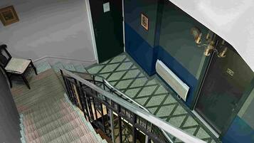 Een trap met een metalen leuning die leidt naar een kamer met een blauwe muur en een deur.