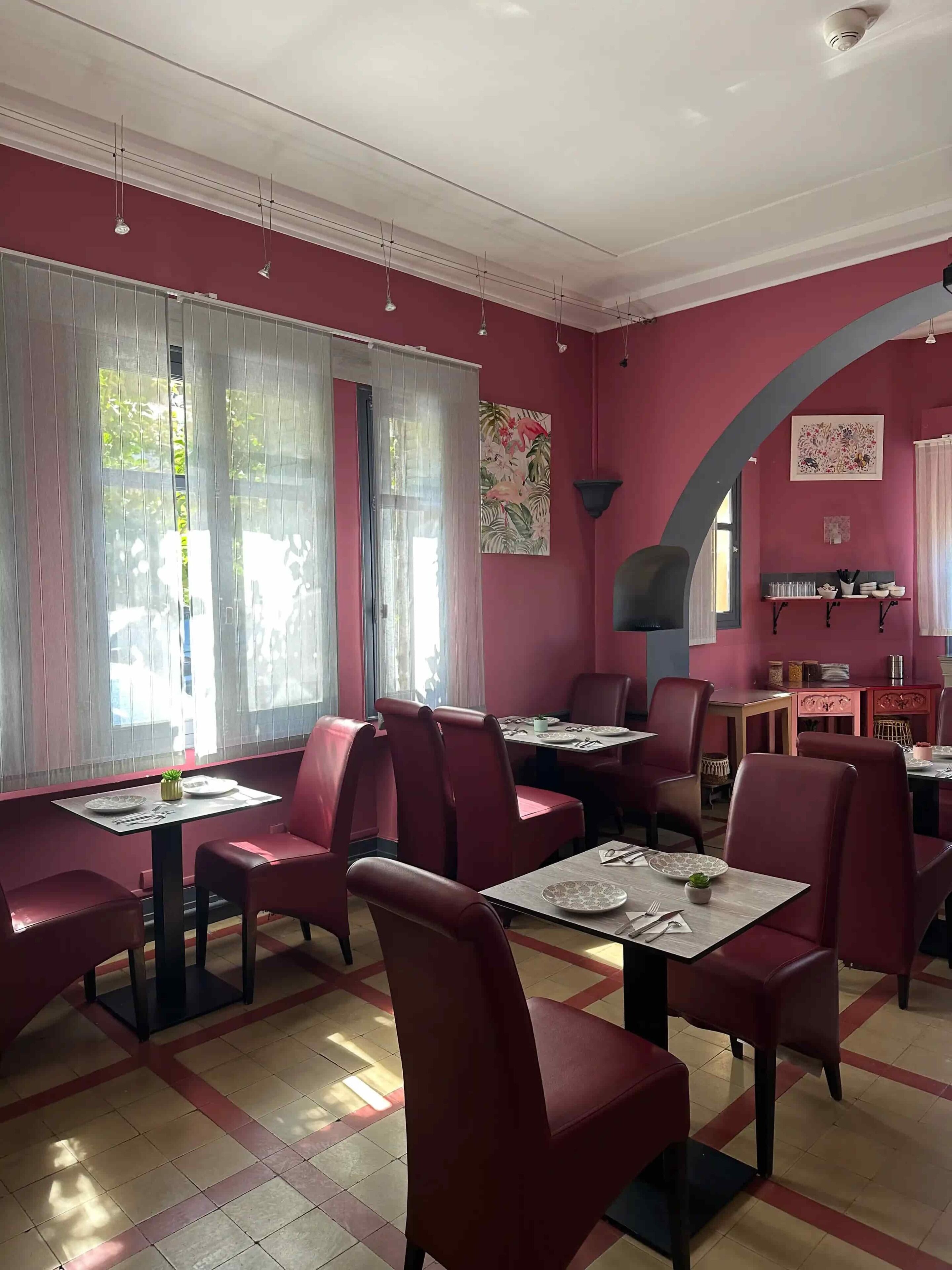 A restaurant interior with red walls, multiple tables, and chairs.