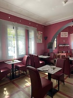 Interior de restaurante con paredes rojas, varias mesas y sillas.