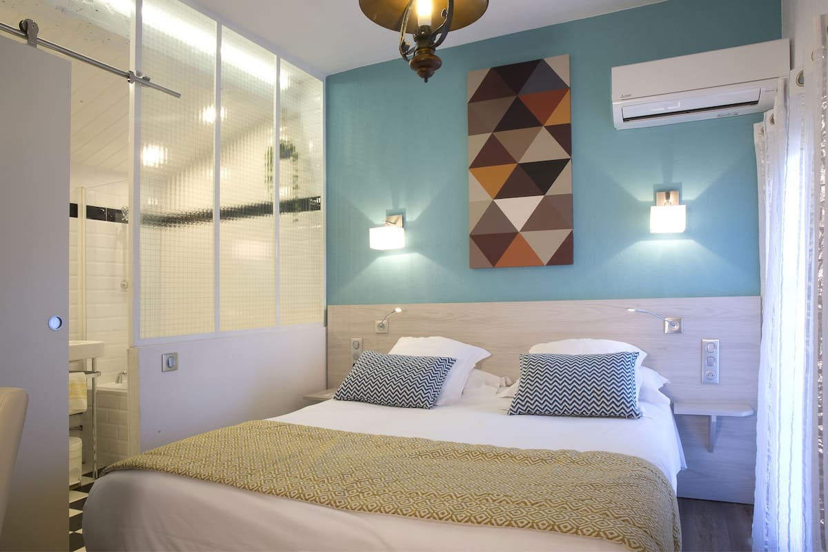 A hotel room with a large bed, a shower, and a wall-mounted air conditioner.
