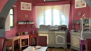 A dining area with a red arch, a projector, and a kitchen counter. - Hôtel Le Mas des Citronniers (Collioure)