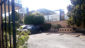 Entrada de un hotel con un cartel que dice 'HOTEL SAINT MICHEL' y un estacionamiento con dos coches.