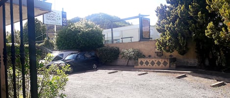 A hotel entrance with a sign for 'HOTEL SAINT MICHEL' and a parking area with two cars.
