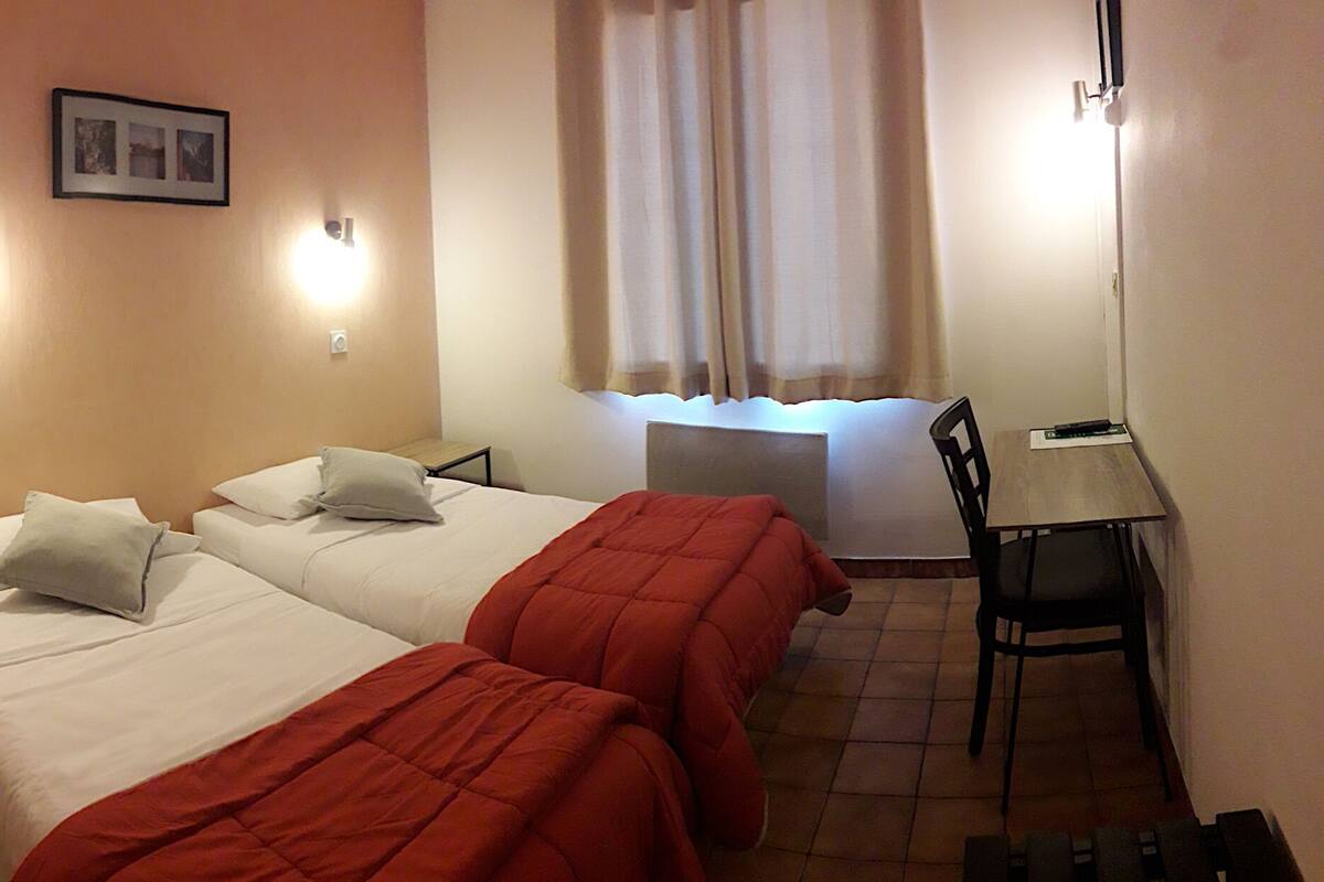 Habitación de hotel con dos camas, un escritorio y una silla.