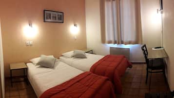 A hotel room with two beds, a desk, and a chair.